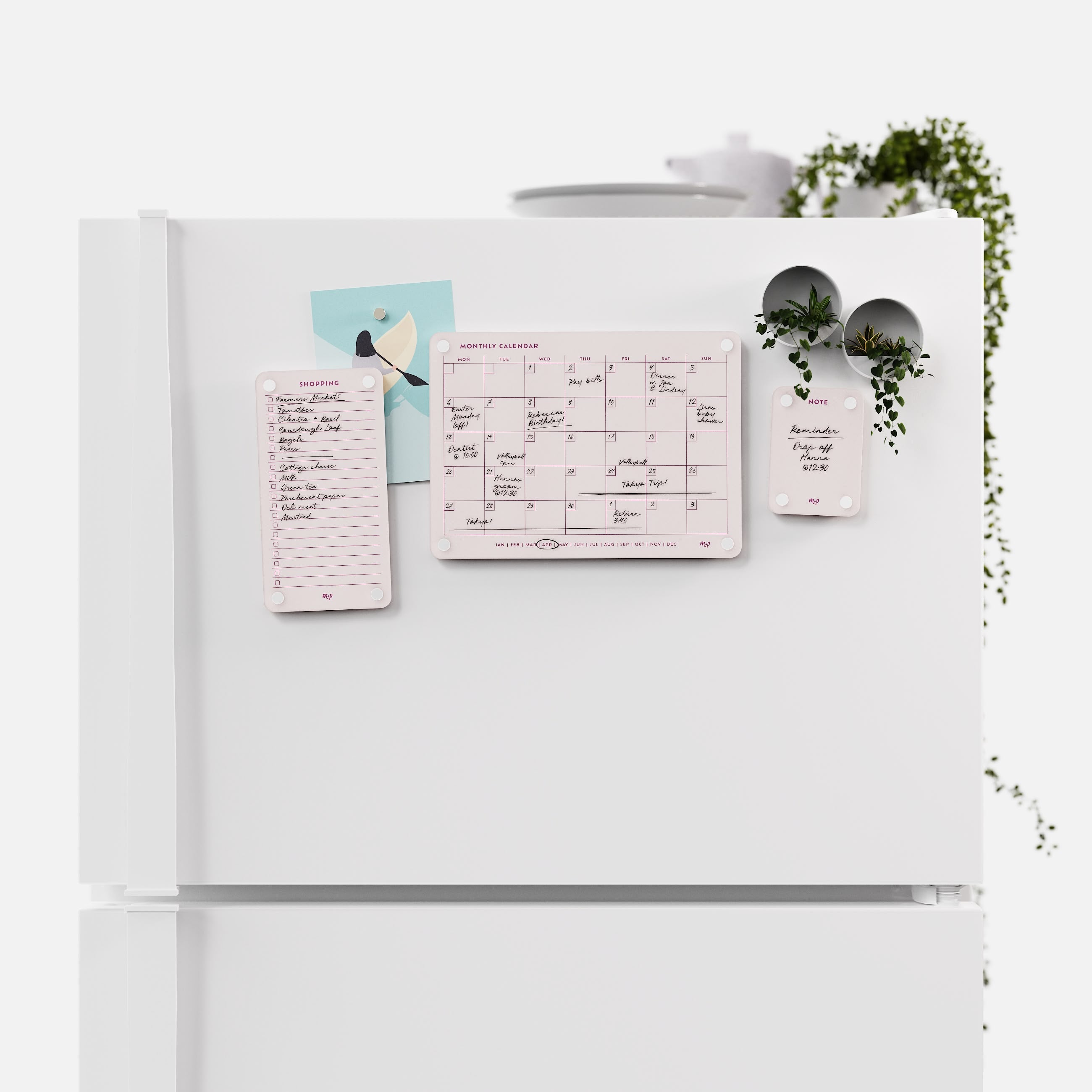 Linen white shopping list, monthly calendar and note board arranged across a white fridge door